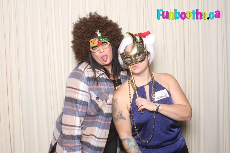 Two guests in an afro wig and a masquerade mask at a costume party photo booth